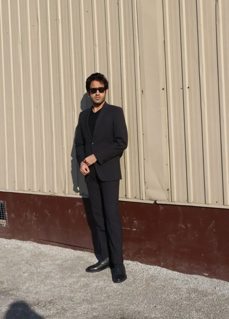 Black suit black v neck sweater and black boots to Dress Better for Guys 