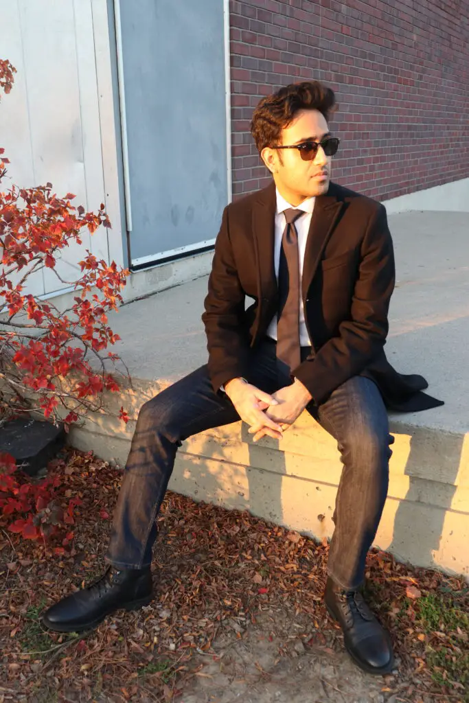 white dress shirt with black tie dark blue jeans black boots and black business casual topcoat